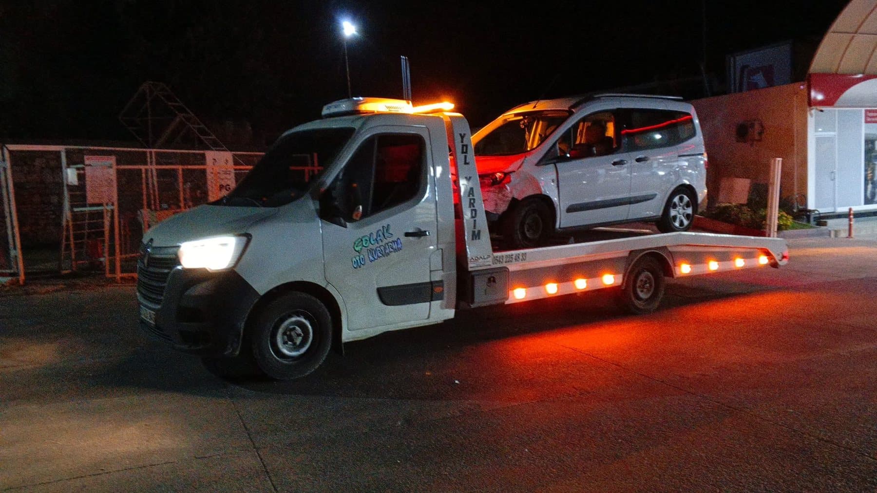 Gece, kasasında kazalı araç taşıyan Çolak Oto Kurtarma çekicisi, yanıp sönen ışıklarla