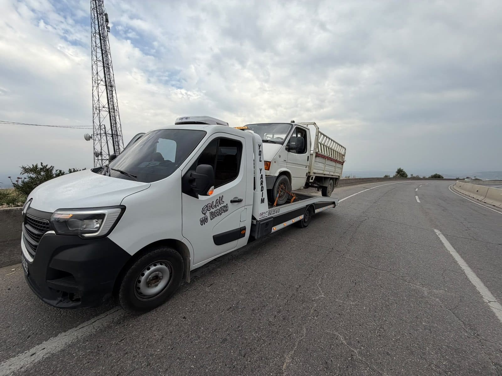 Virajlı dağ yolunda, kasasında küçük kamyonet taşıyan Çolak Oto Kurtarma çekicisi