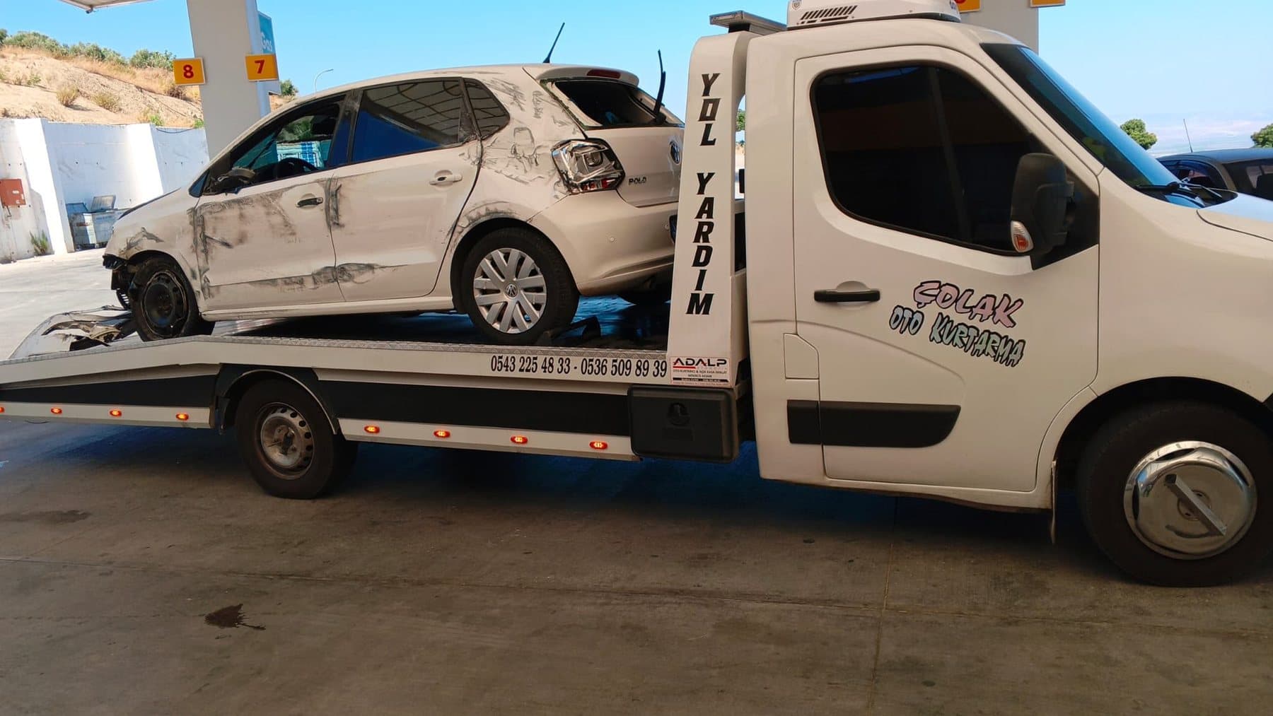 Kazalı beyaz hatchback otomobili kasasında taşıyan Çolak Oto Kurtarma çekicisi