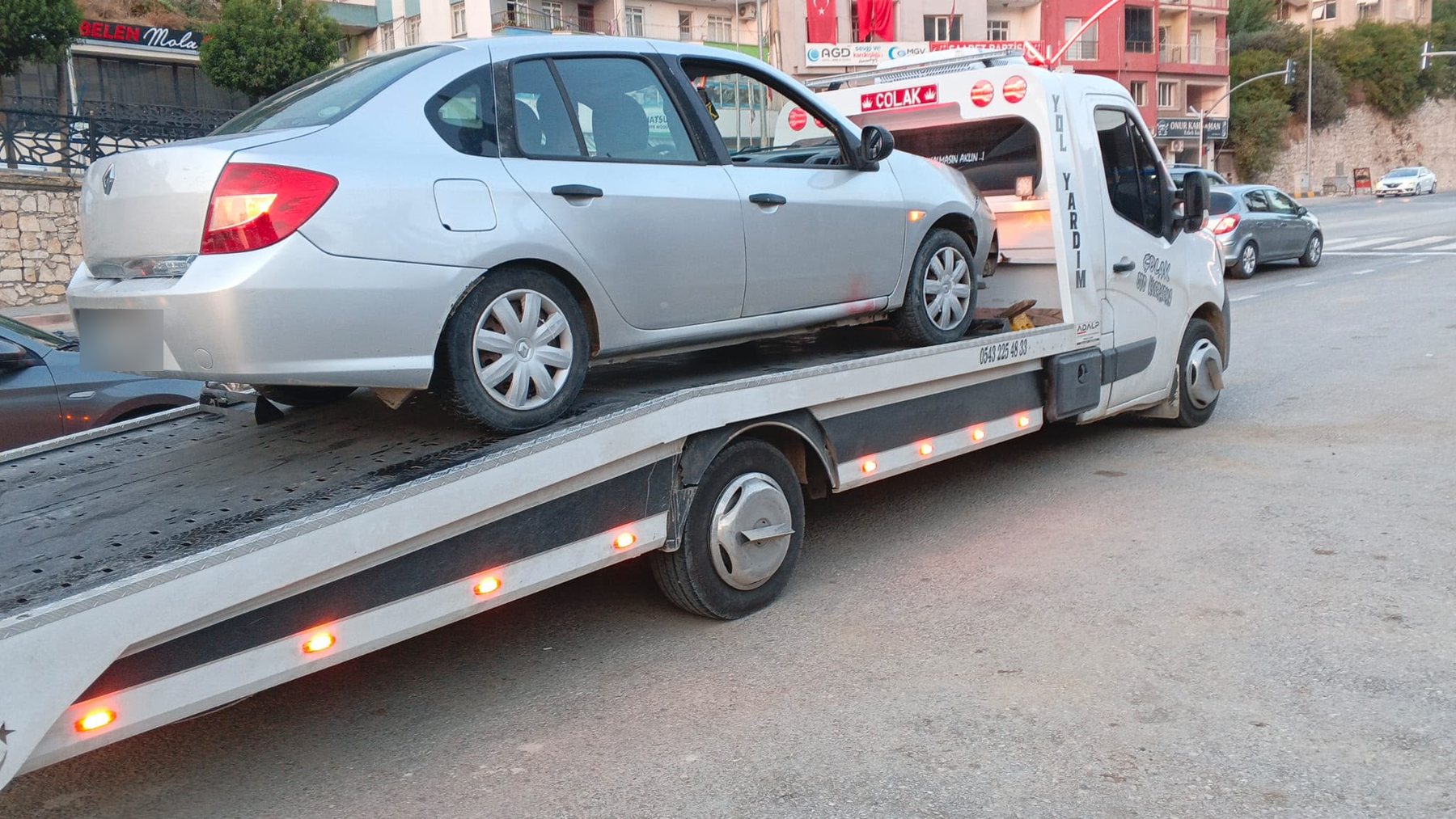 Şehir içinde kasasına gri sedan yüklenmiş Çolak Oto Kurtarma çekicisi